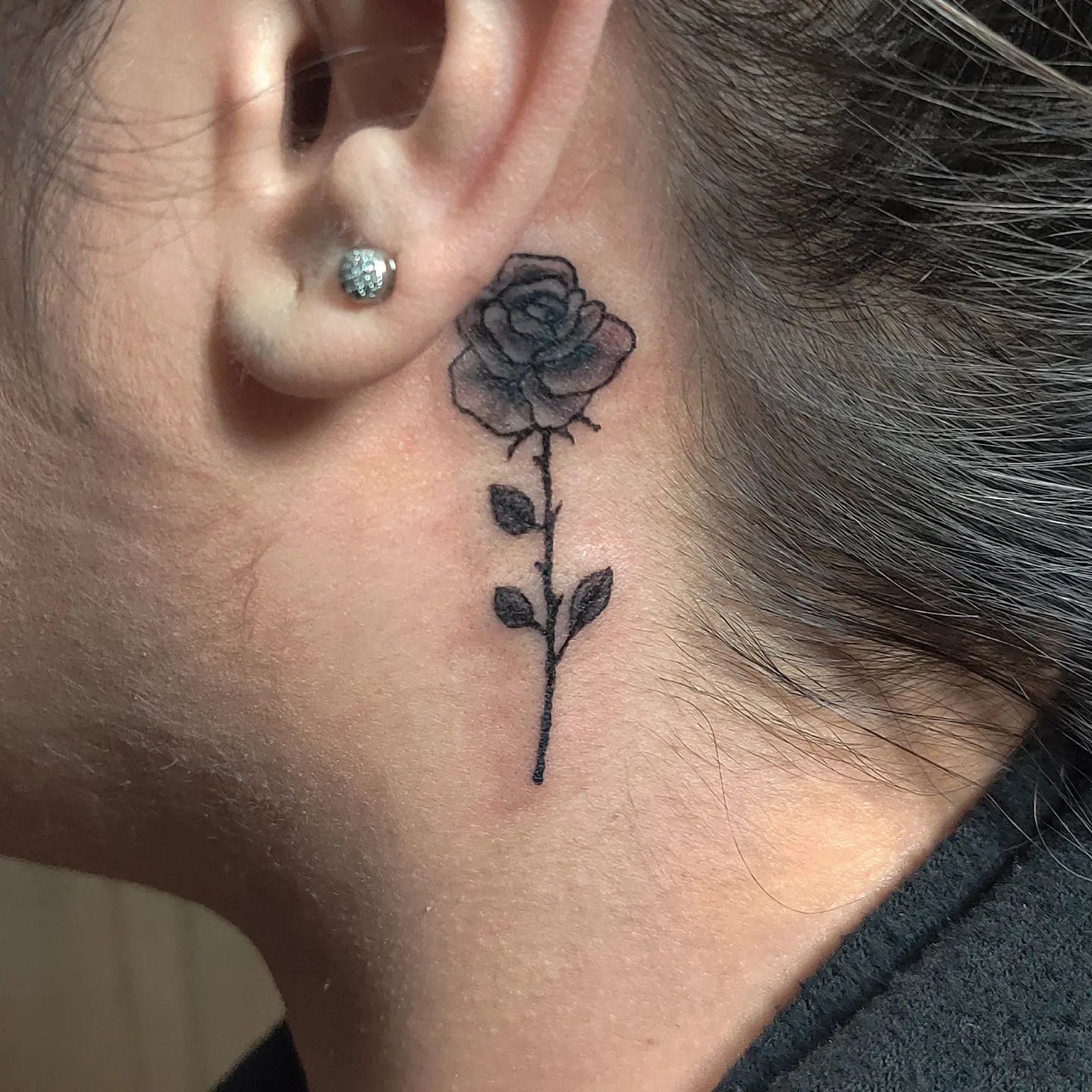 Tatuaje de rosa detrás de la oreja