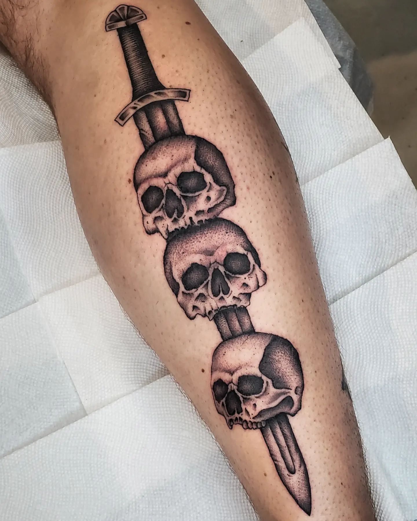 Cuchillo y tatuaje de cráneo en la pantorrilla