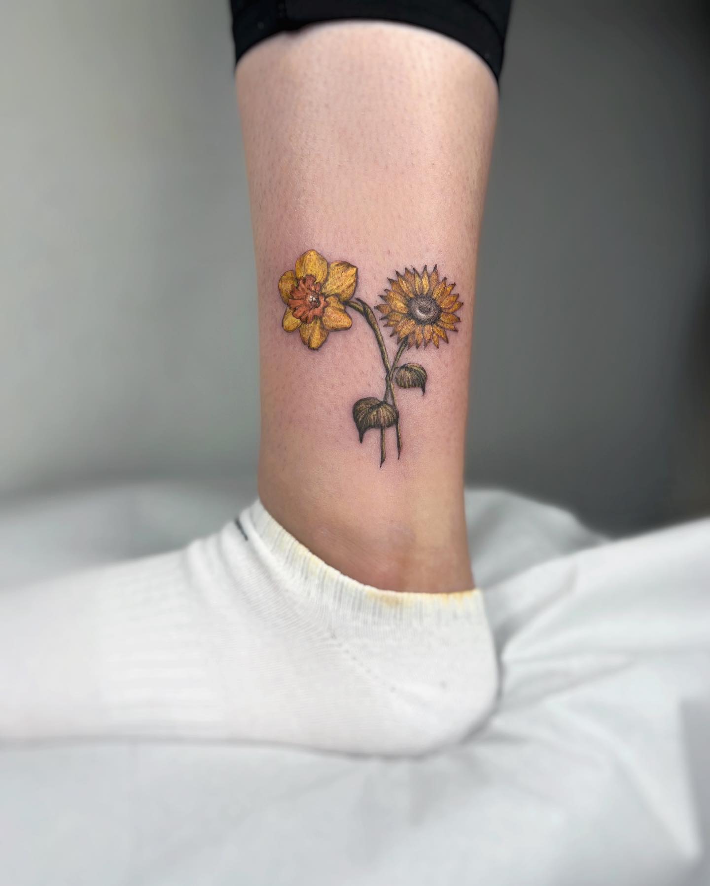Pequeño tatuaje de narciso en el tobillo.