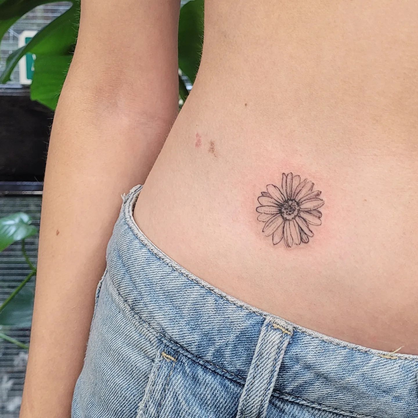 Tatuaje de margarita negra en la espalda.