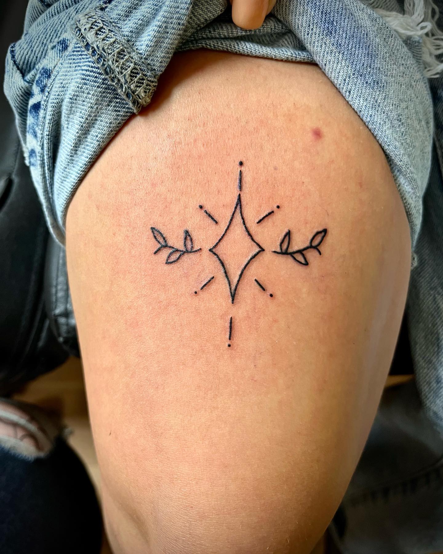 Tatuaje de tinta negra encima de la rodilla