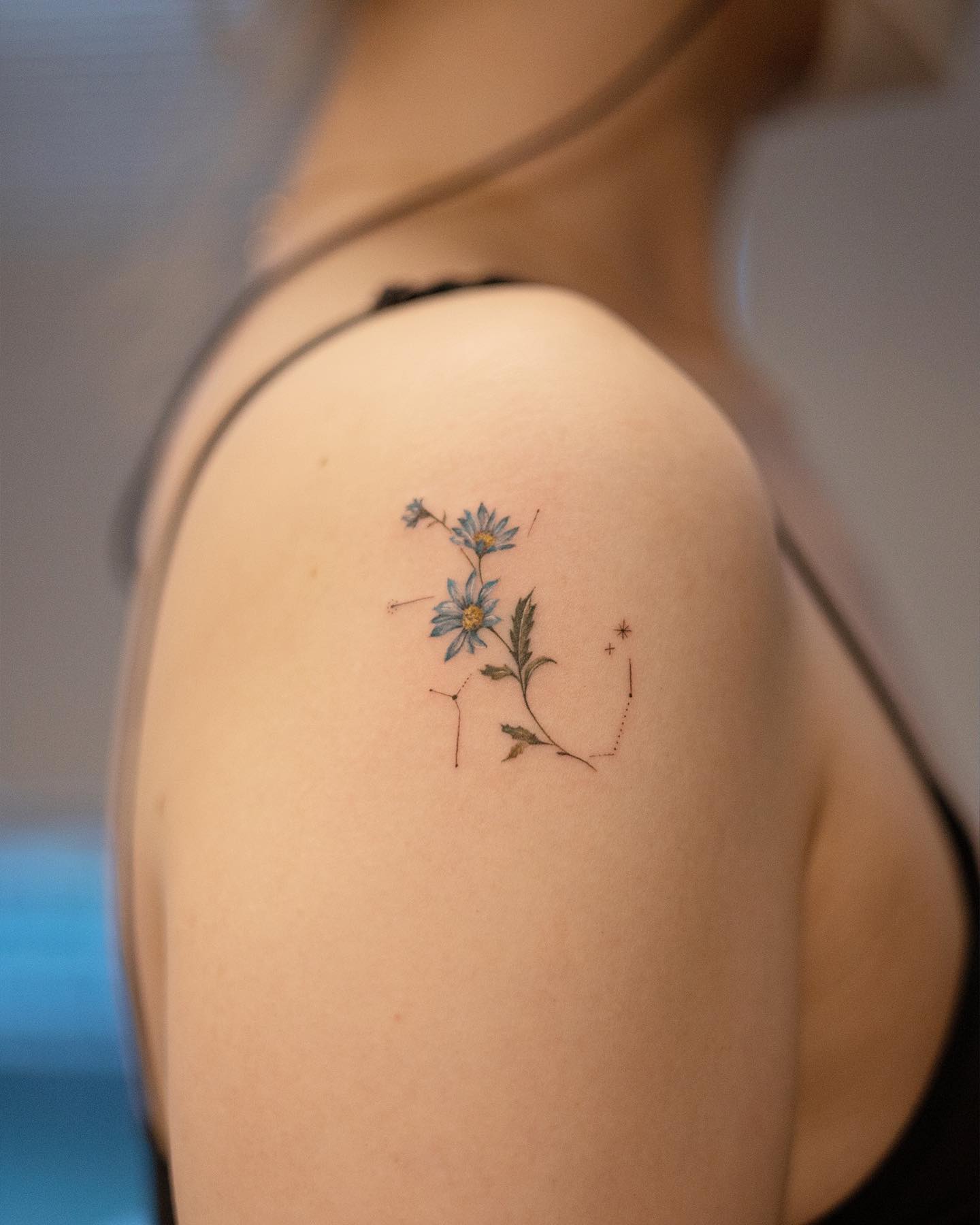 Tatuaje pequeño de margarita en el hombro