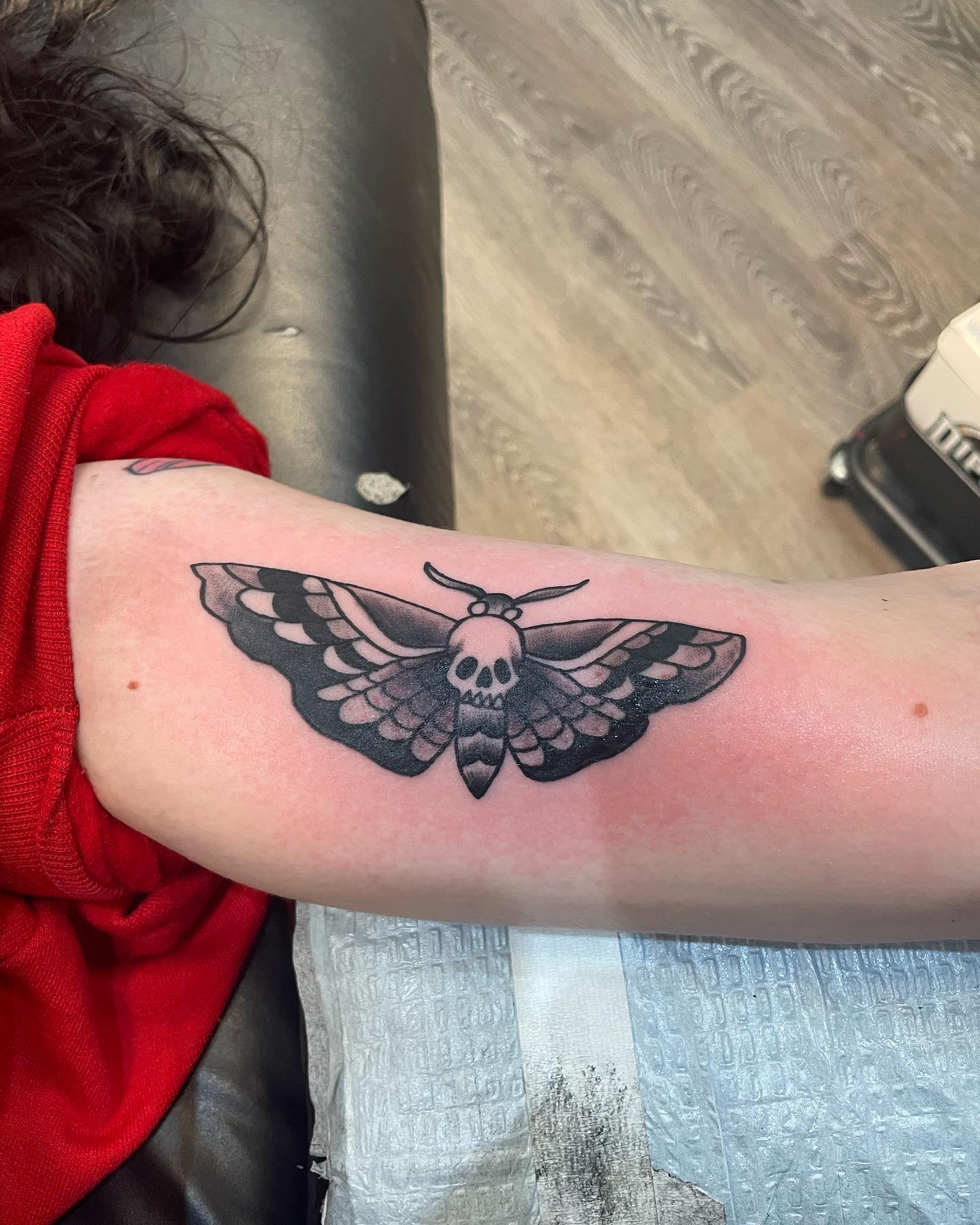 Diseño de tatuaje de polilla negra en el brazo.