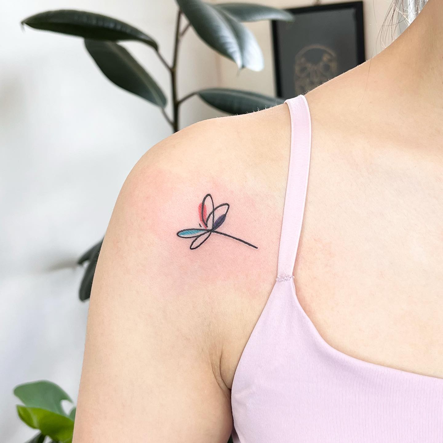 Pequeño tatuaje de libélula en el hombro.