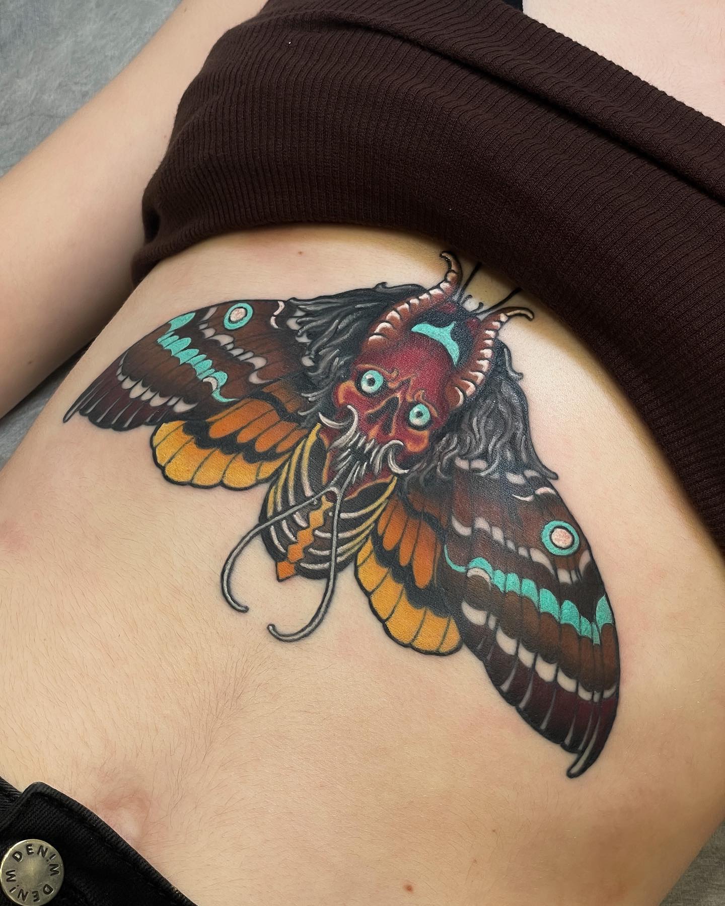 Tatuaje de polilla negra en el estómago.