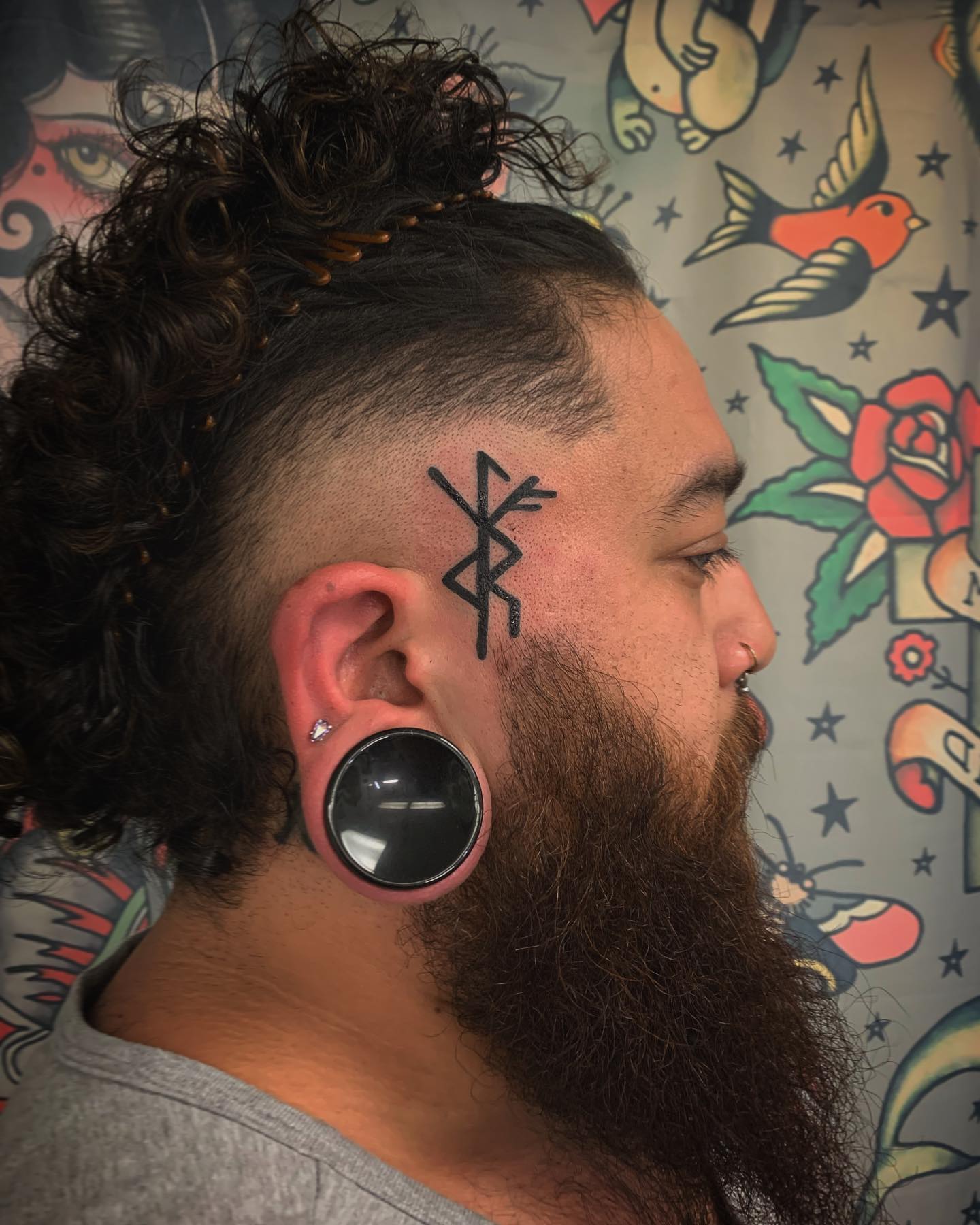 Tatuaje divertido con un símbolo en la cara.