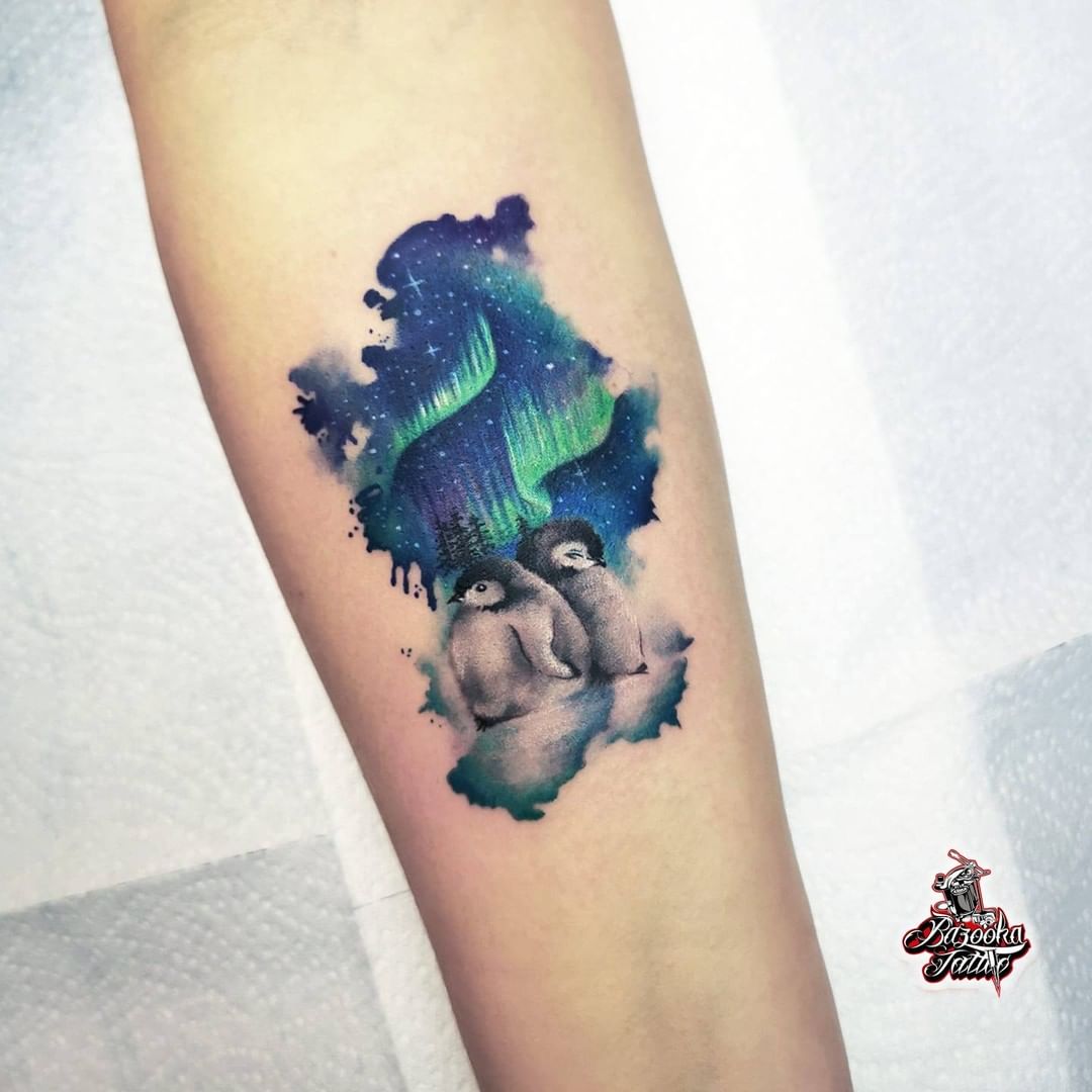 Luces del norte con un tatuaje de pingüino.