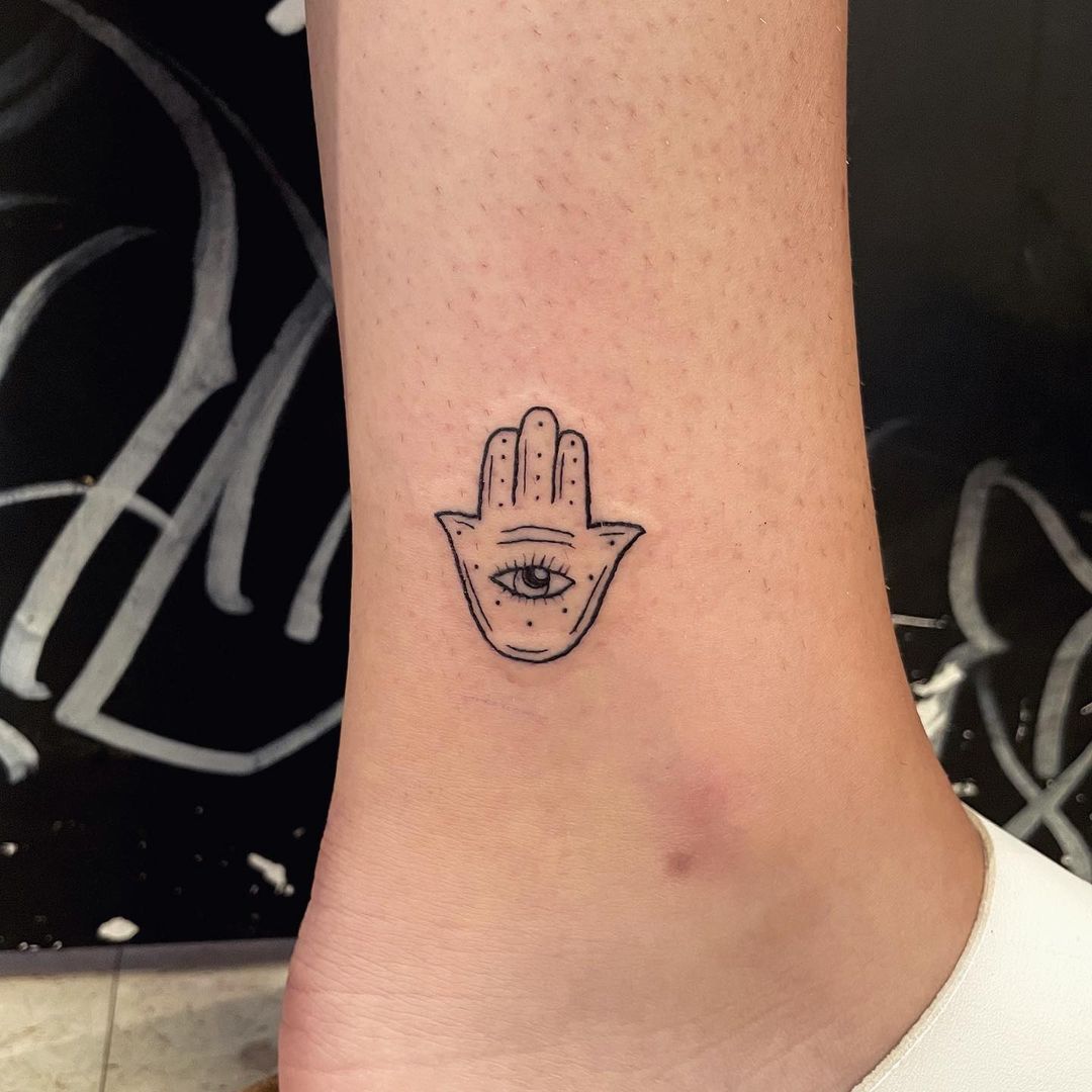 Tatuaje delicado y pequeño de Hamsa en el tobillo.