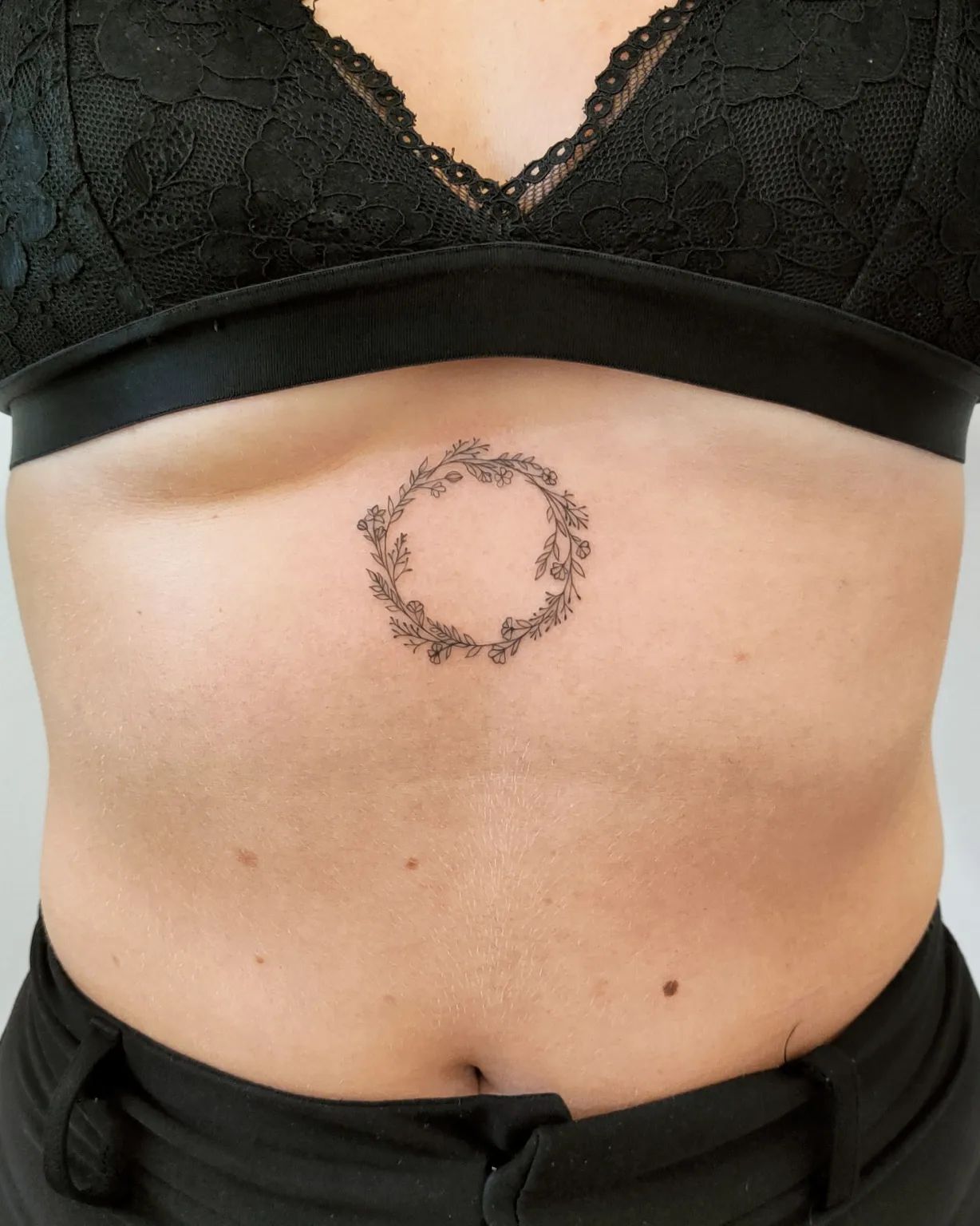 Pequeño tatuaje circular entre los pechos