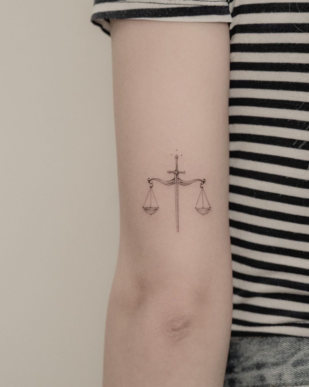 Pequeño tatuaje de la balanza y la espada.