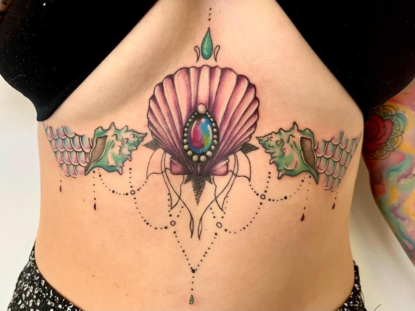 Tatuaje de Concha Colorido entre los Senos