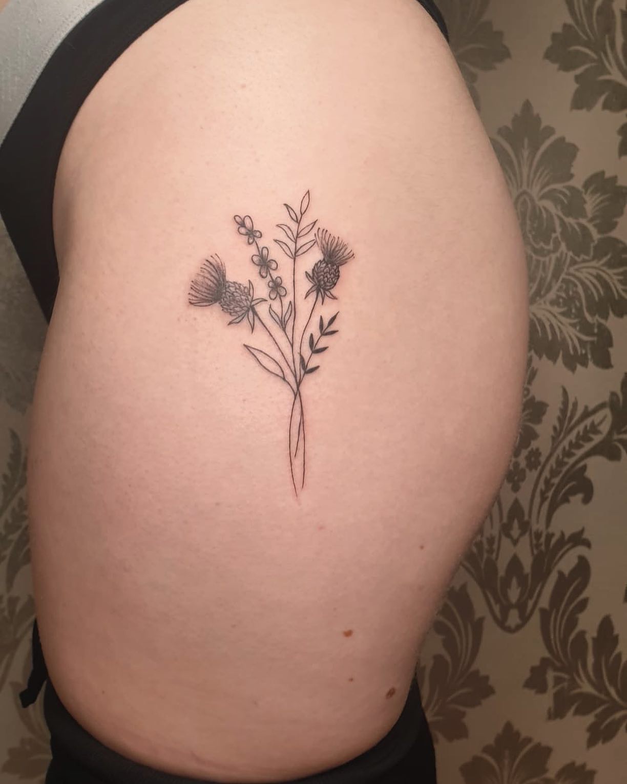 Tatuaje de línea fina en el muslo.