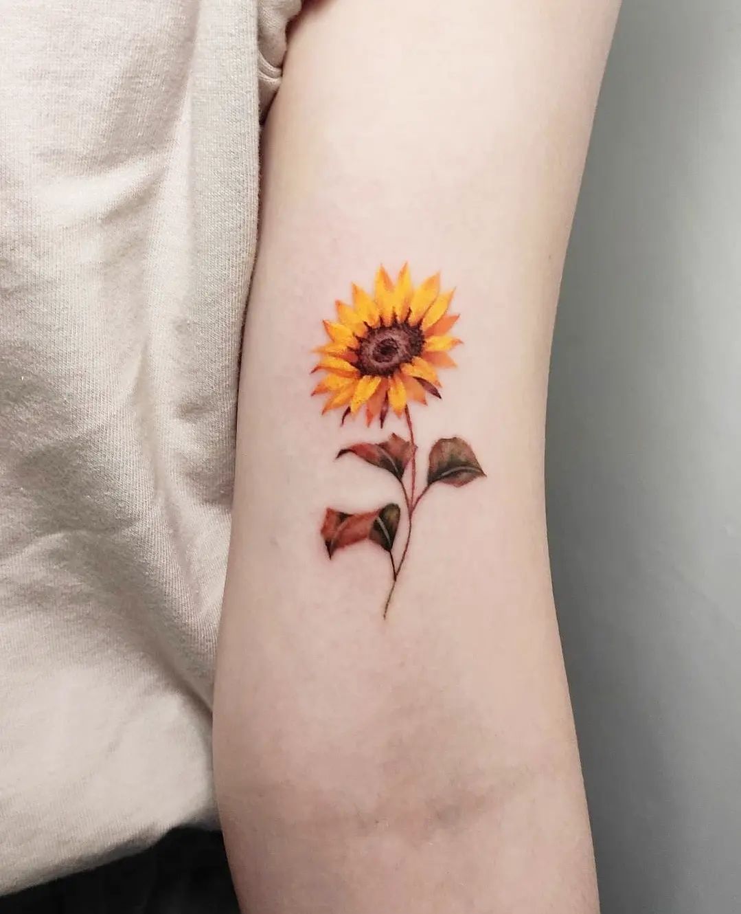 Tatuaje pequeño de caléndula en el antebrazo.
