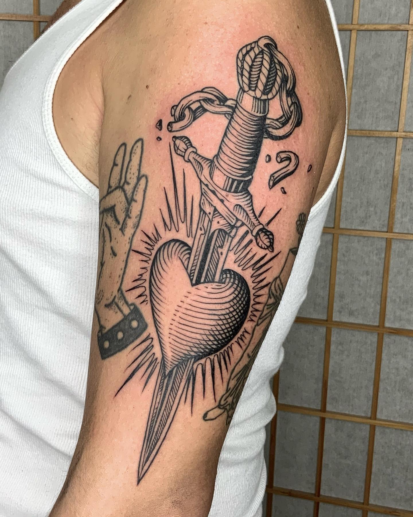 Tatuaje de daga negro y blanco en el brazo.