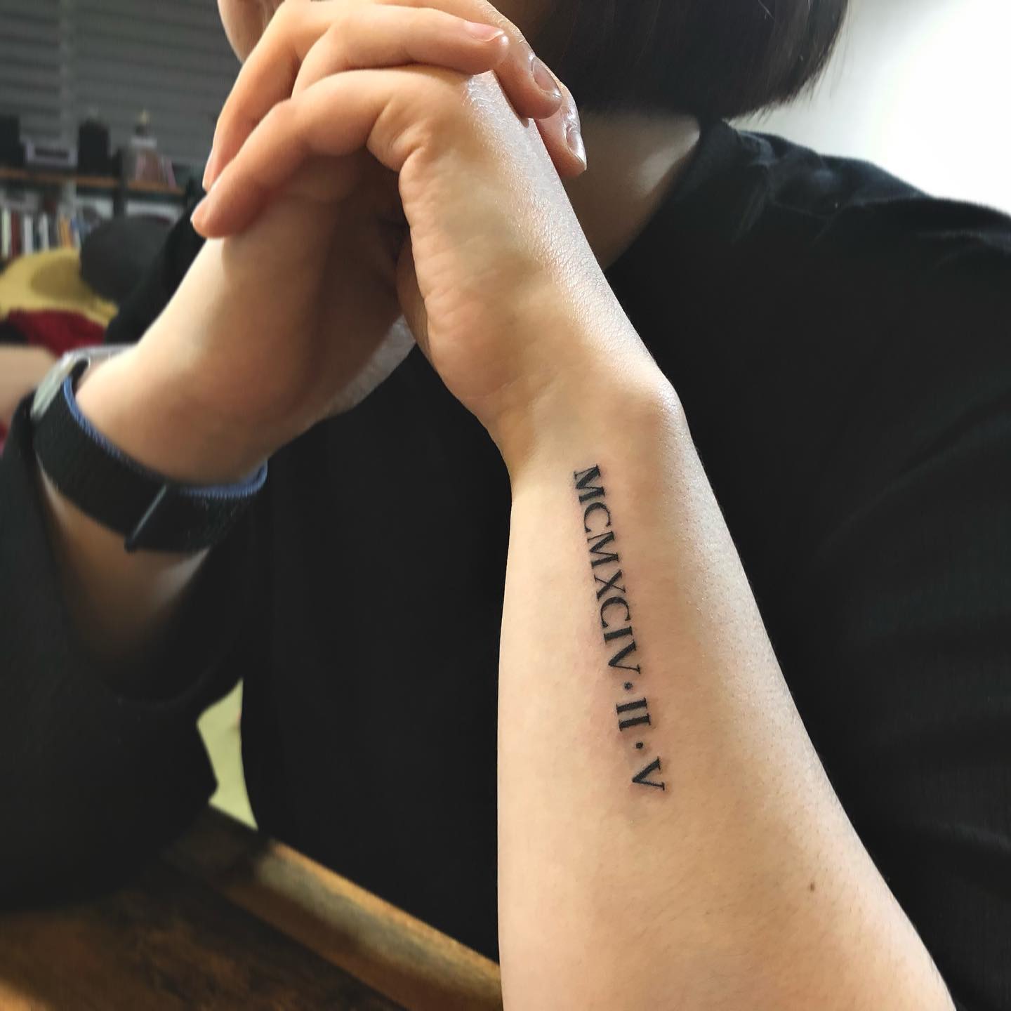 Diseño de tatuaje de número romano en antebrazo.