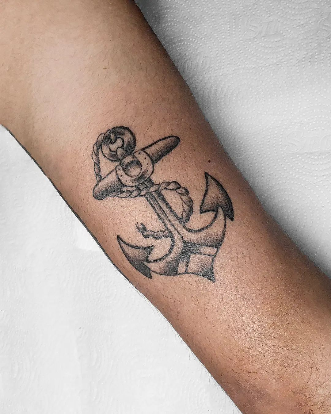 Tatuaje de ancla en la mano, tinta negra.