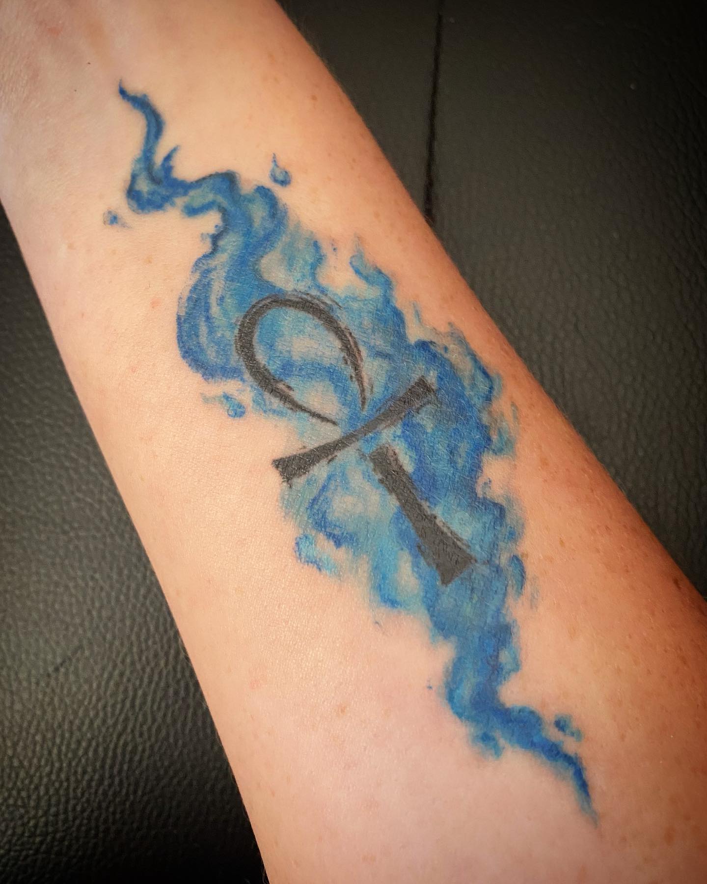 Tatuaje de Ankh de estómago azul y dorado.