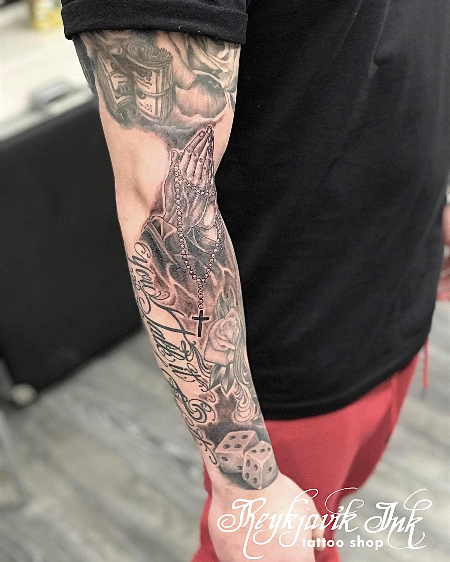 Tatuaje de manos rezando en el antebrazo.
