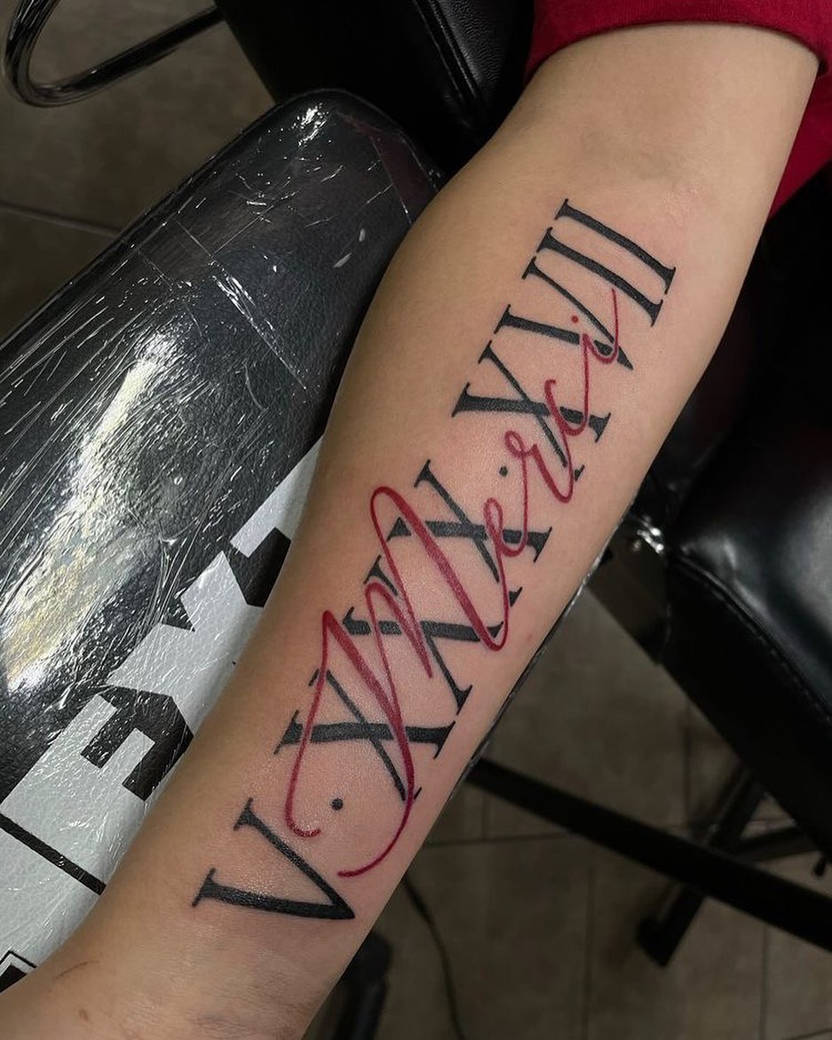 Tatuaje de número romano con tinta roja.