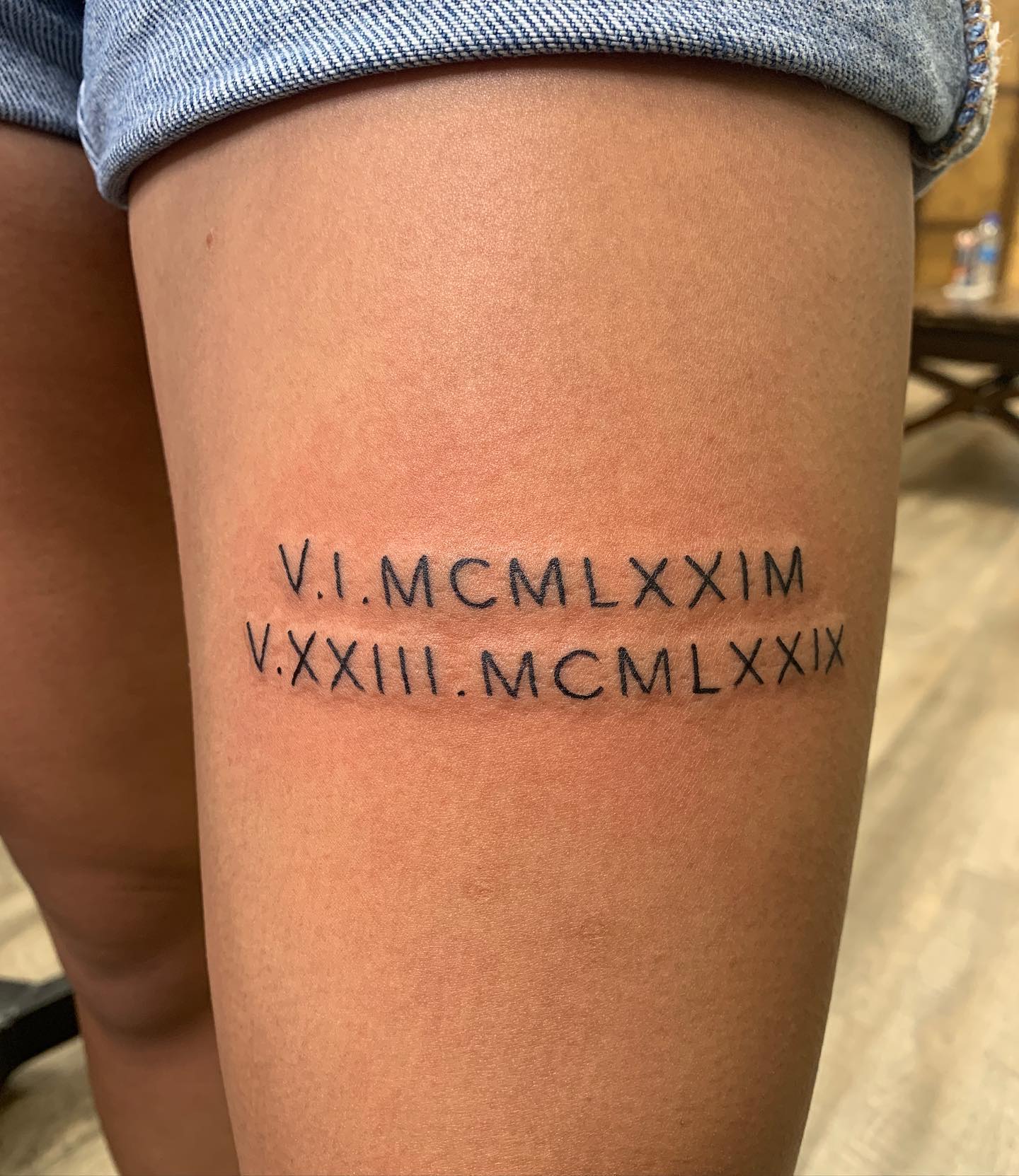 Tatuaje de número romano en el muslo.