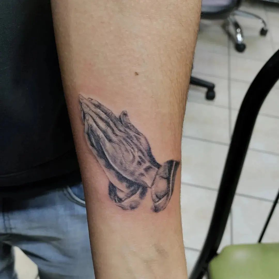 Tatuaje minimalista de manos rezando.