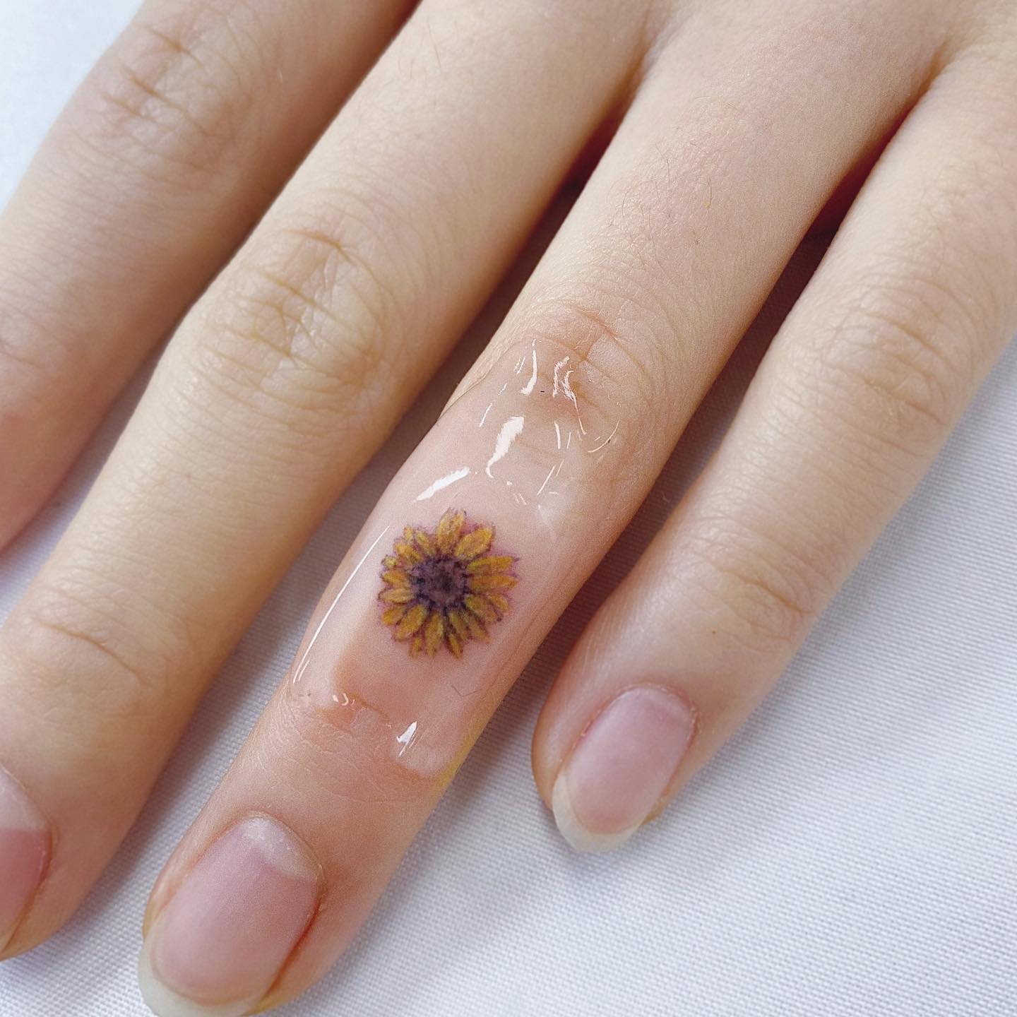 Tatuaje de girasol en el dedo