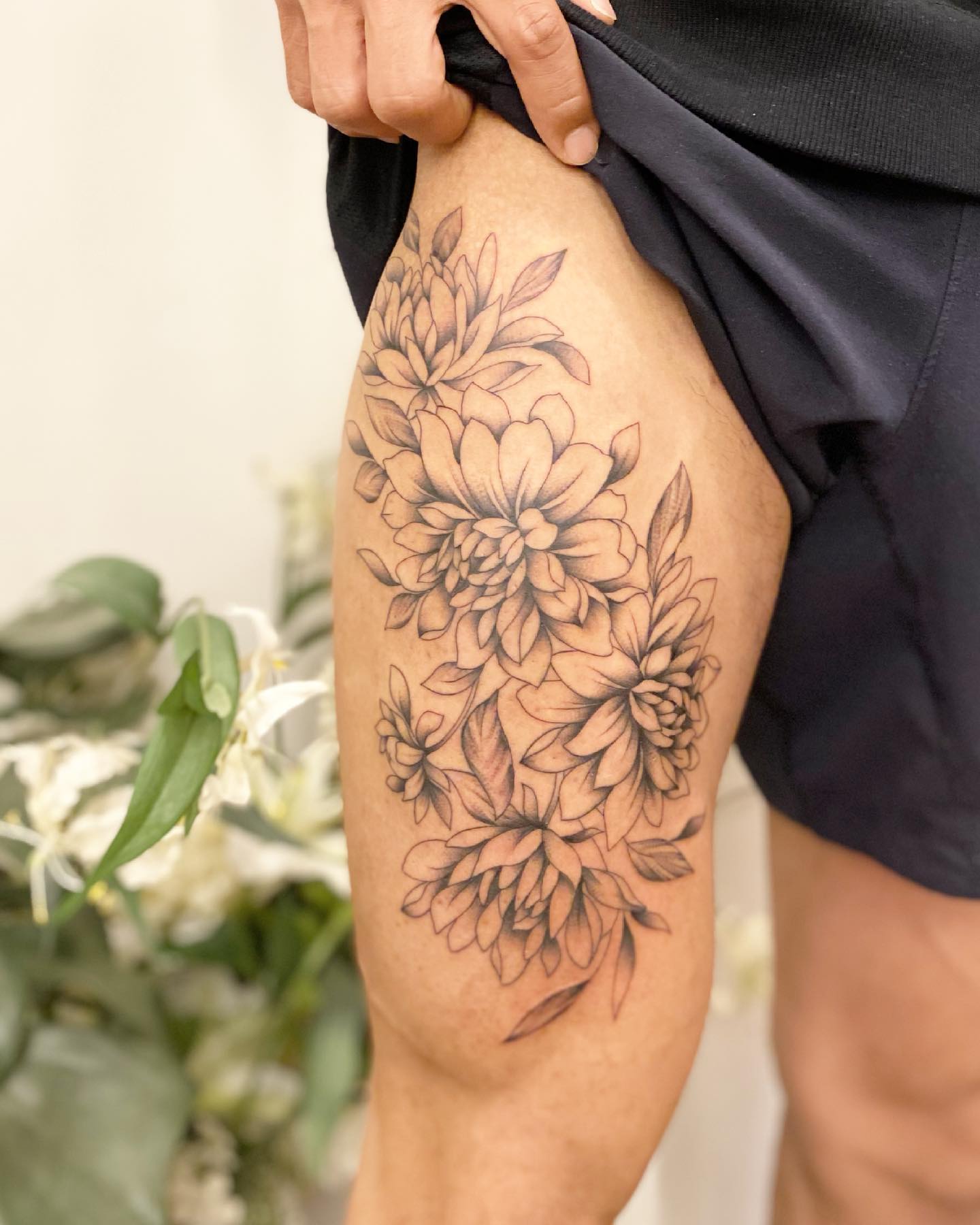 Tatuaje floral en el muslo para hombres.