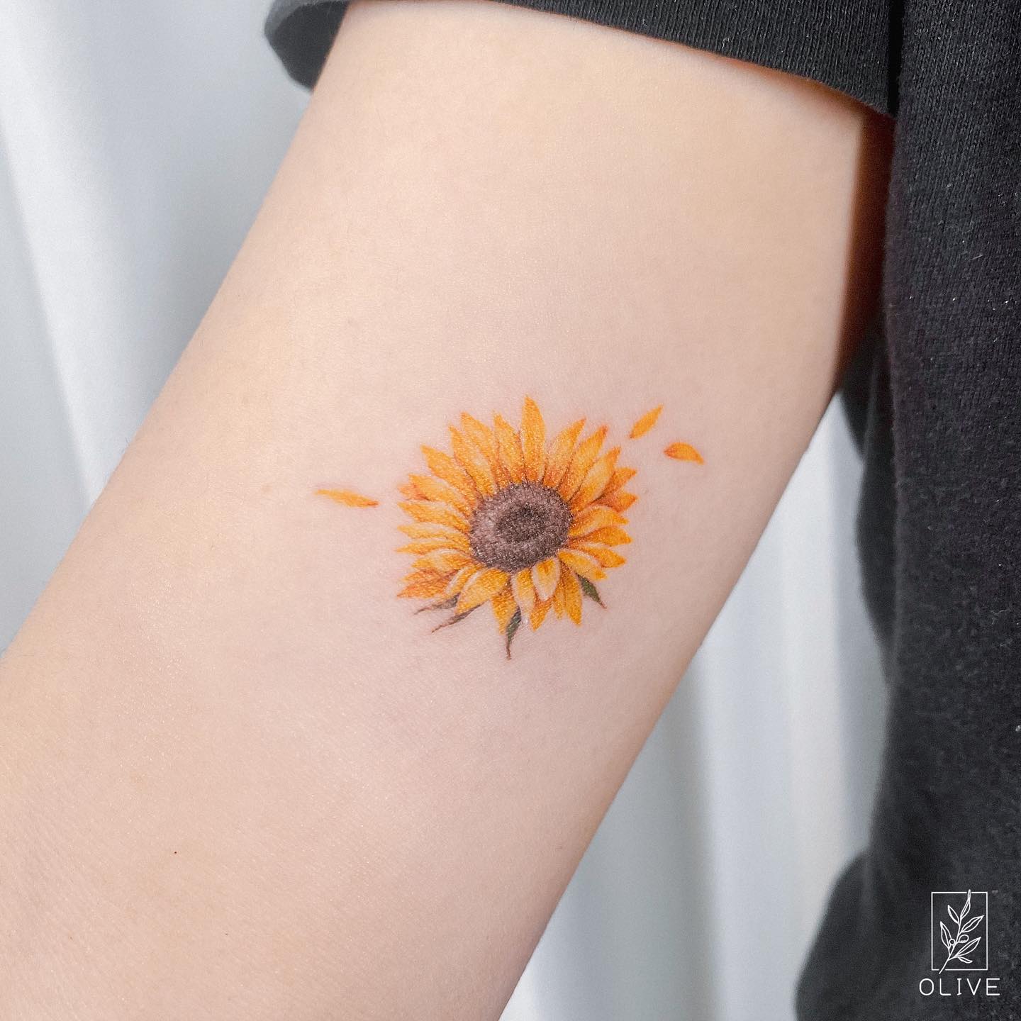 Tatuaje pequeño de girasol naranja.