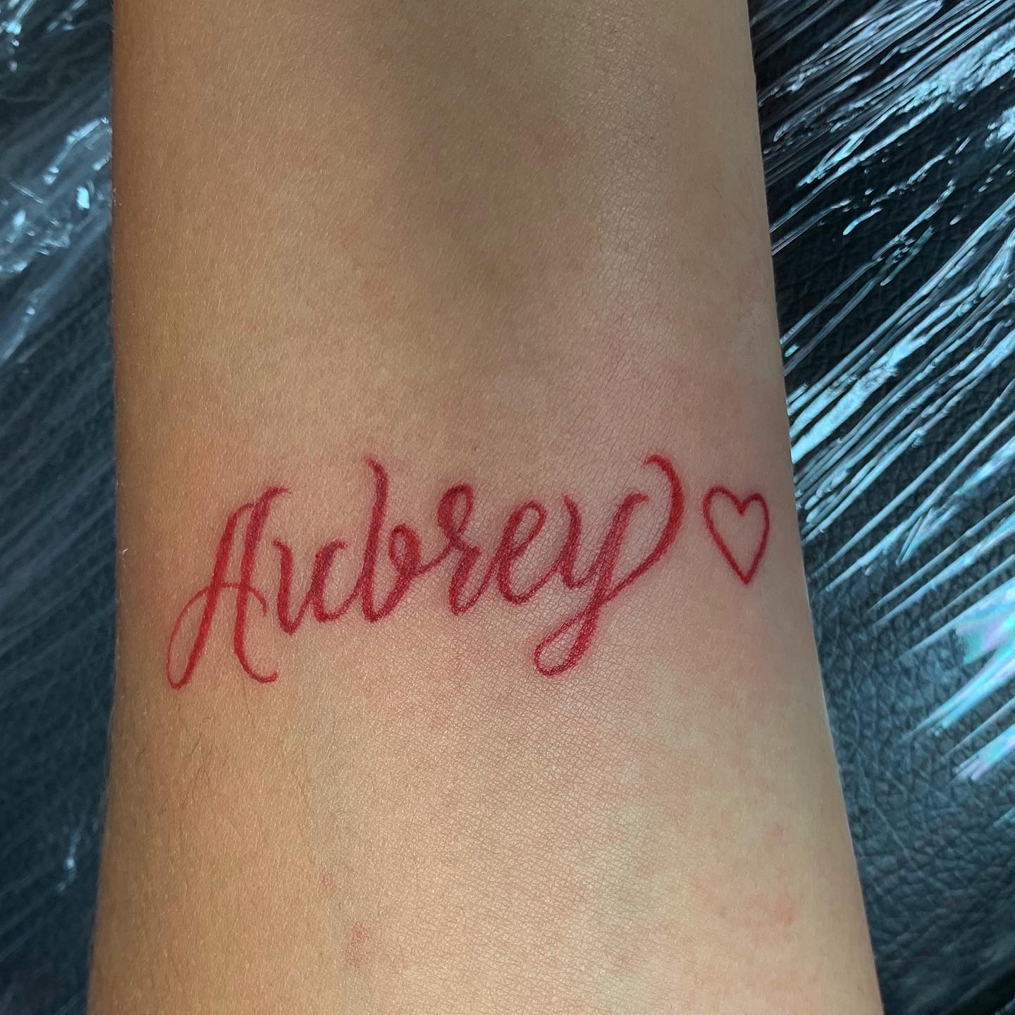 Tatuaje de nombre de hijos en tinta roja