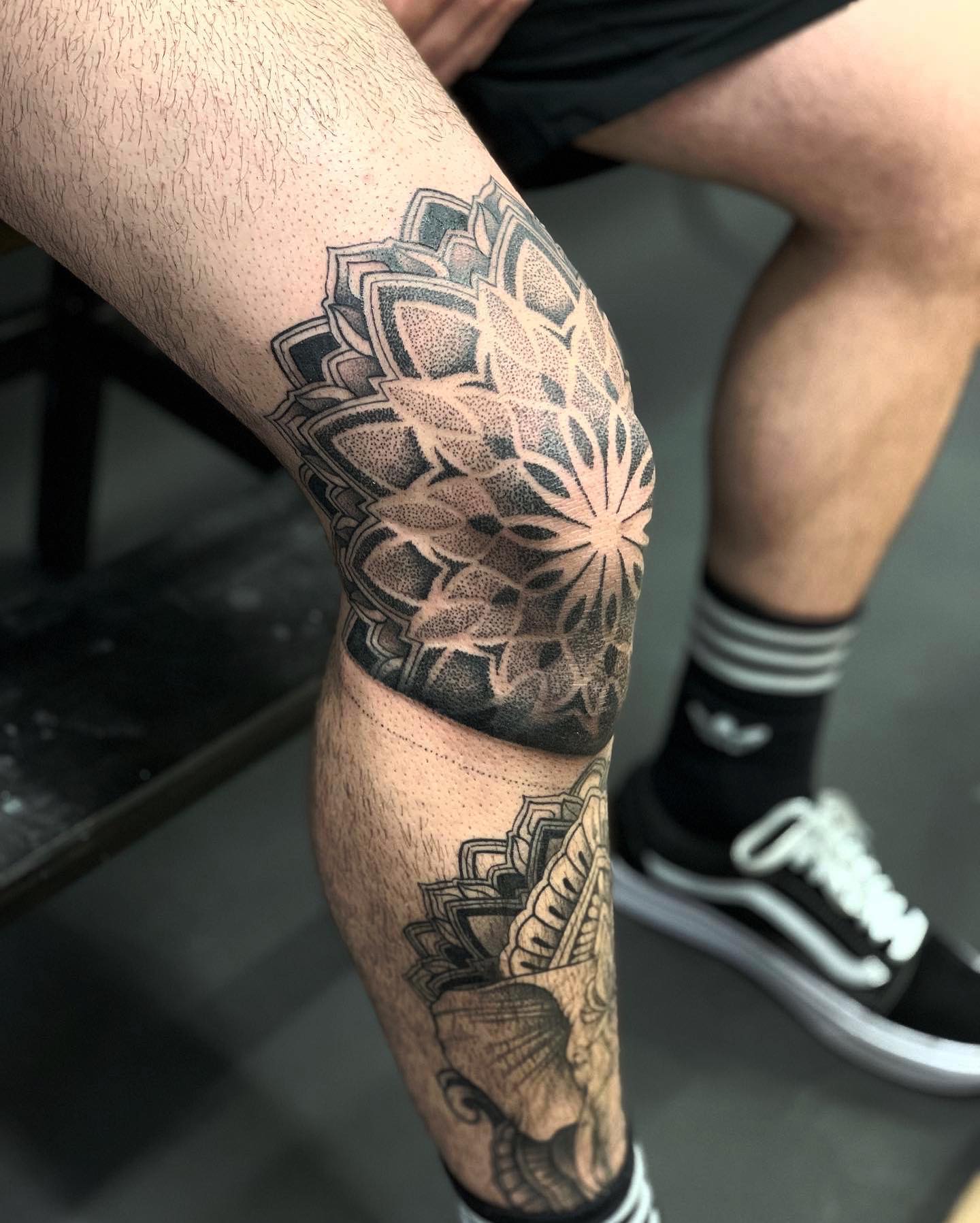 Tatuaje de rodilla en tinta negra de mandala.
