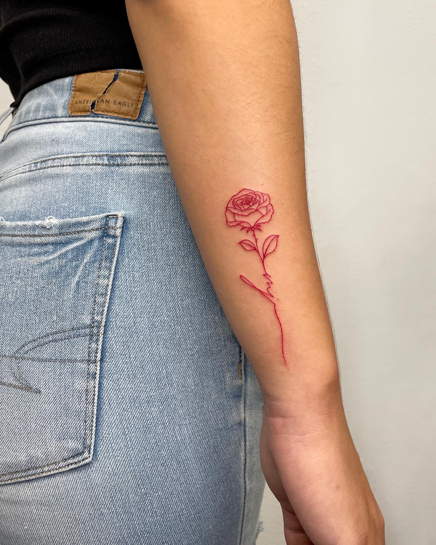 Pequeño tatuaje de rosa roja brillante.