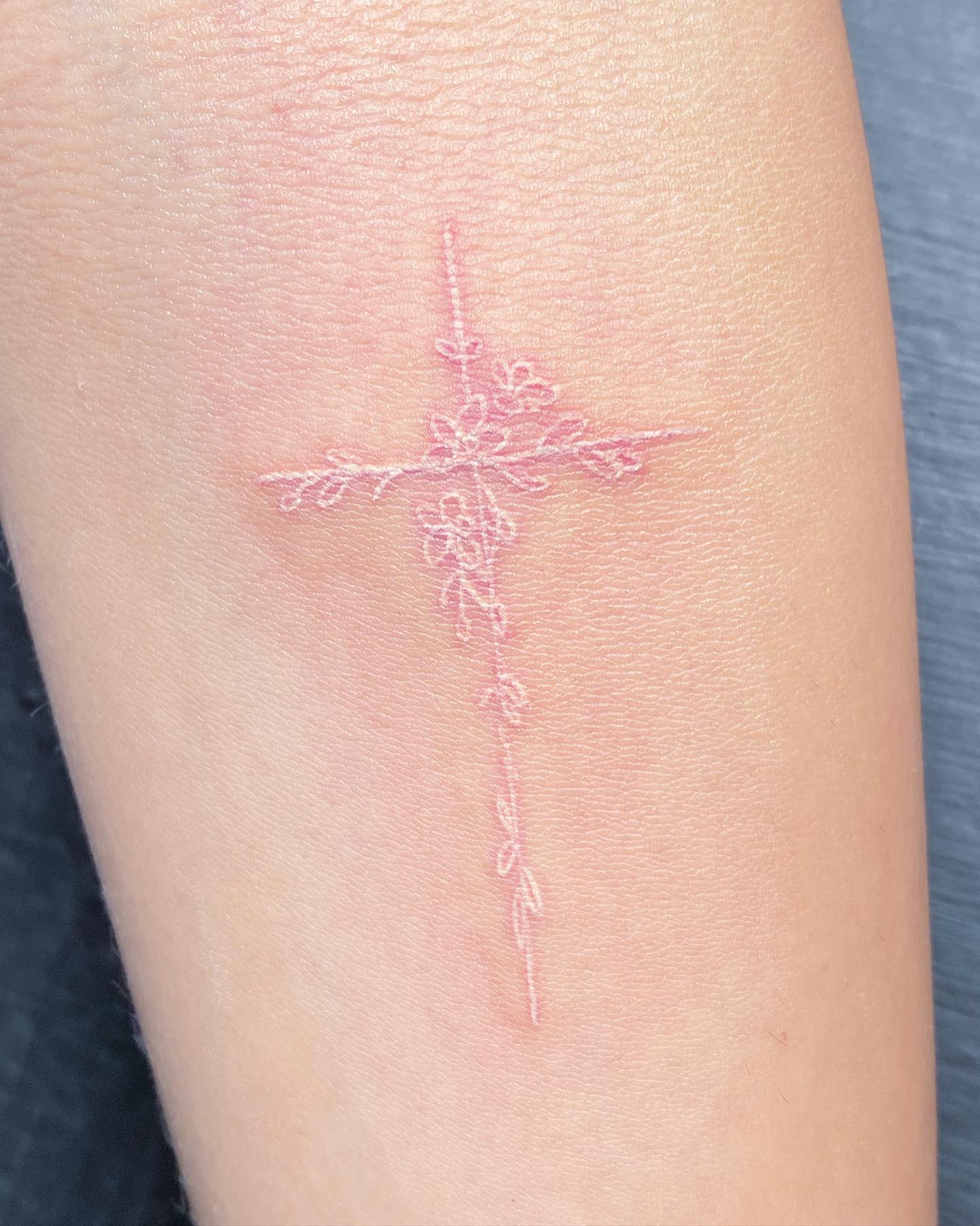 Tatuaje de cruz con tinta blanca.
