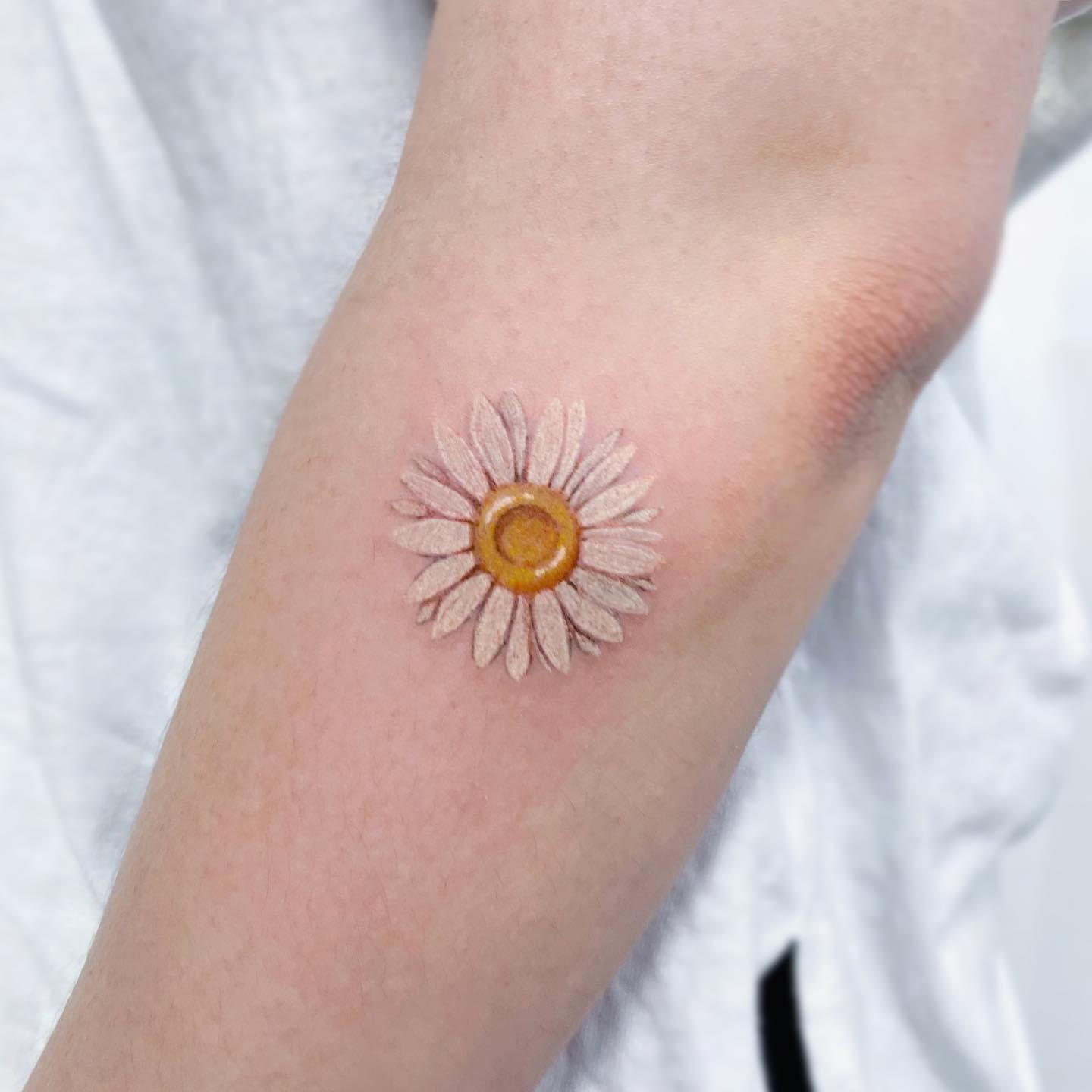 Tatuaje de margarita con tinta blanca