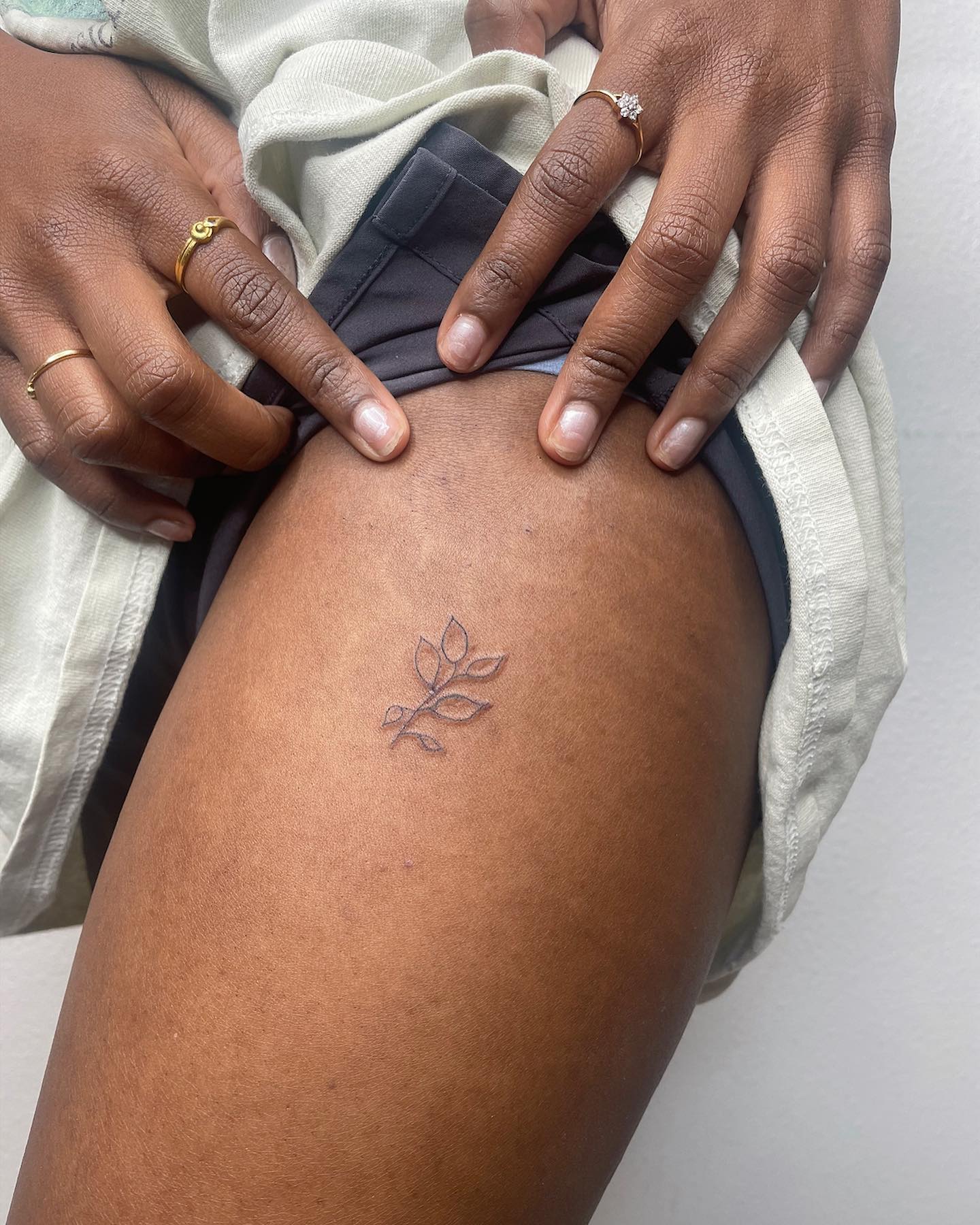 Tatuaje minimalista de hoja en muslo superior