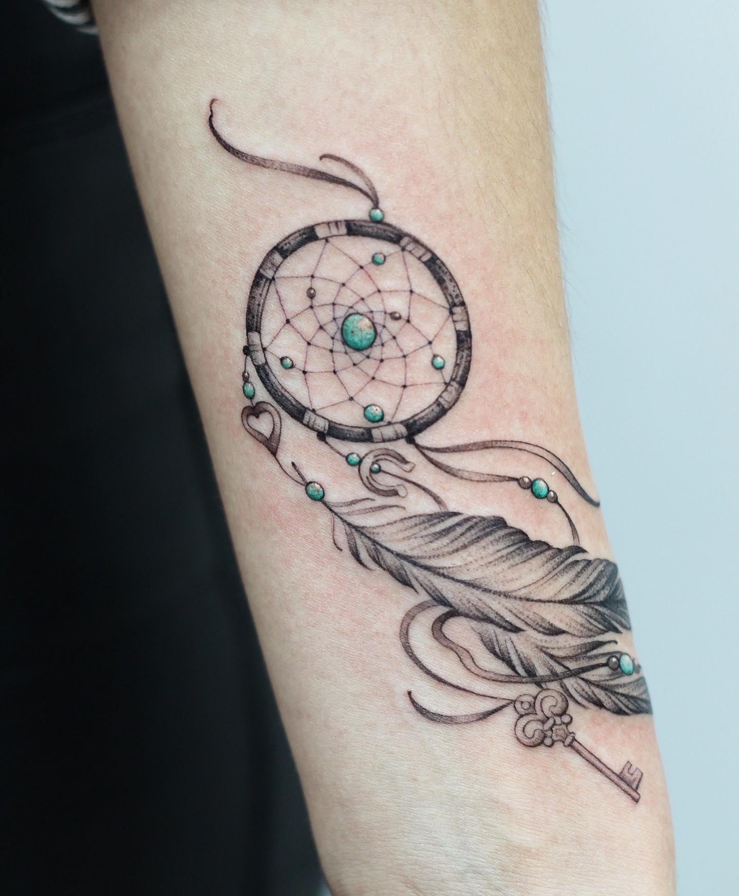 Tatuaje de atrapasueños con piedras verdes