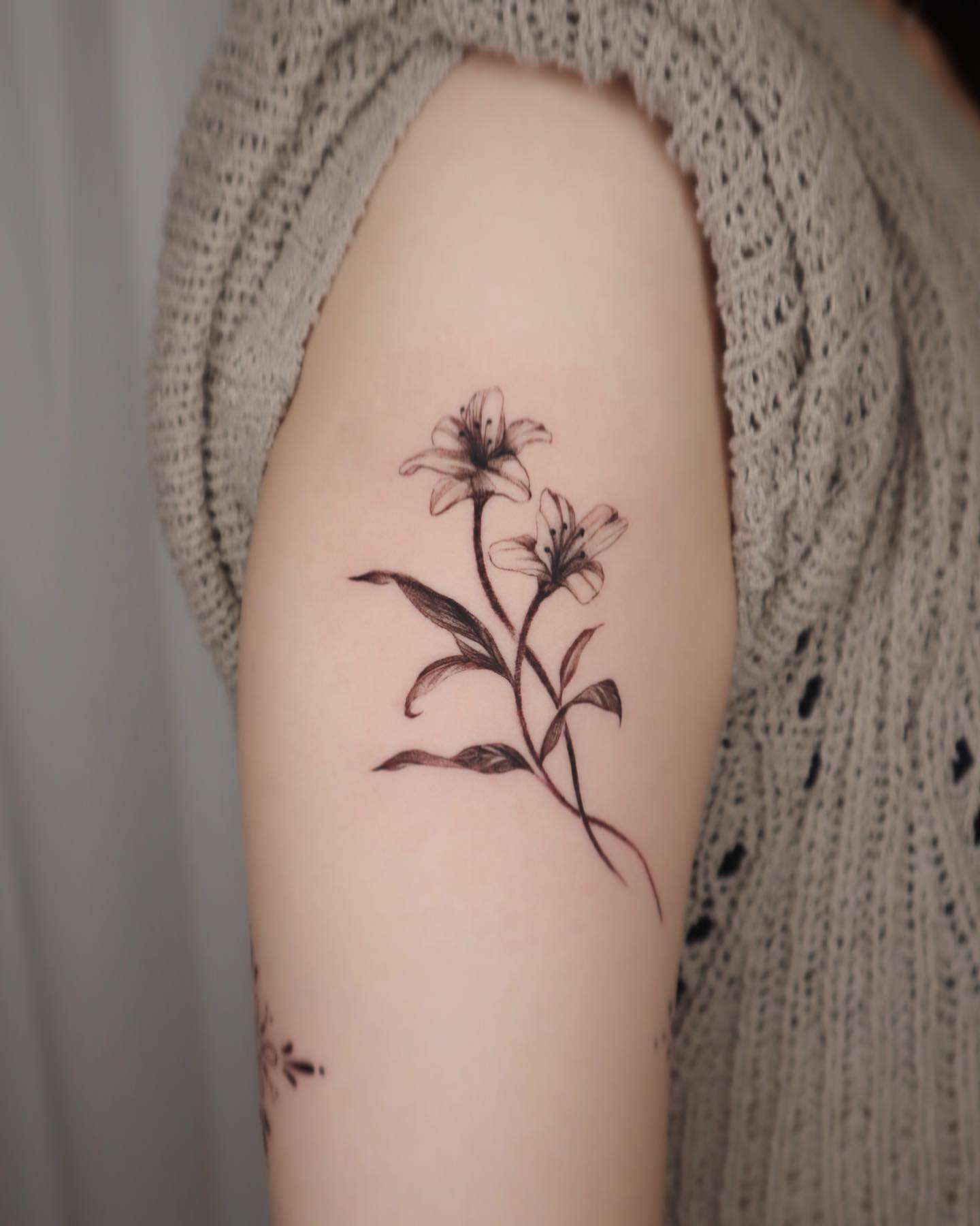 Tatuaje de lirios en blackwork en el brazo.