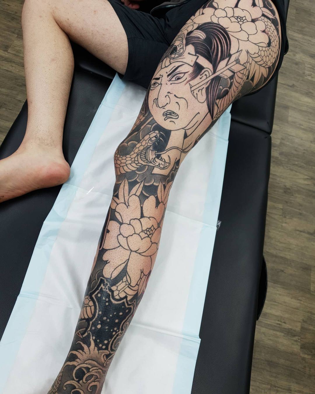 Tatuaje Namakubi con tinta negra en muslo gigante.