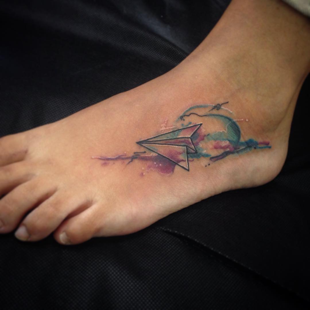 Tatuaje de avión de papel en el brazo.
