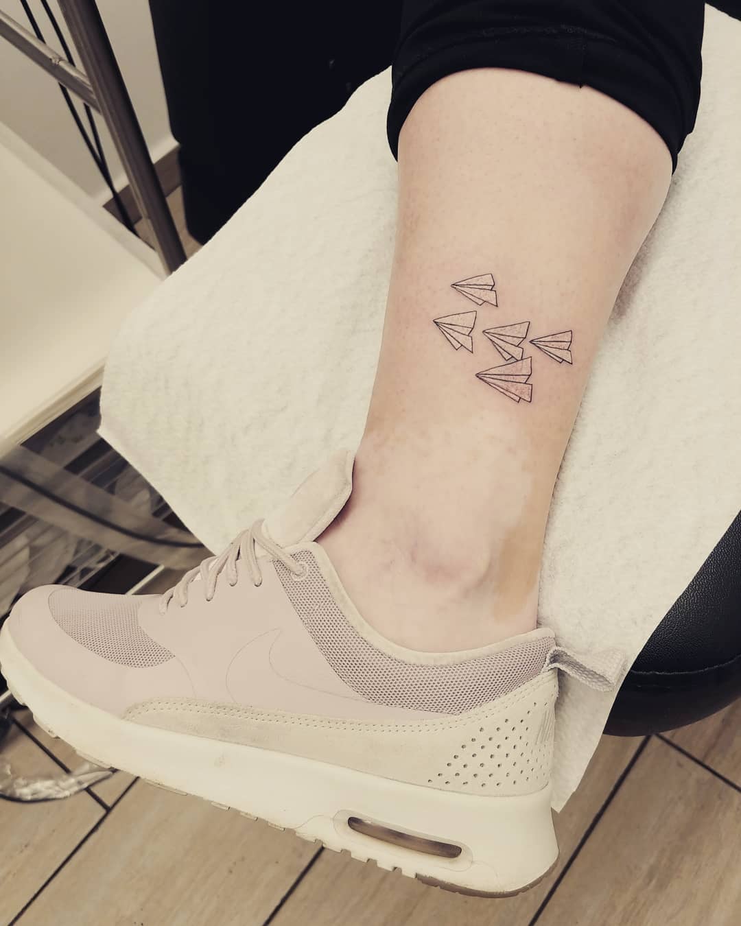 Tatuaje de avión de papel inspirado en viajes.
