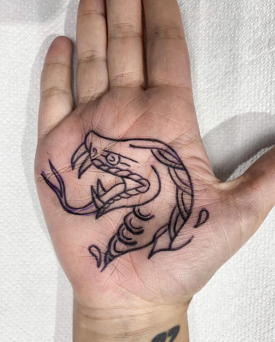 Tatuaje de serpiente en el antebrazo, tinta negra.