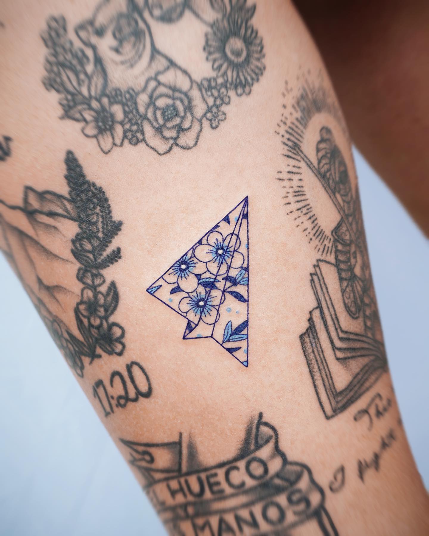 Tatuaje de un avión de papel naranja.