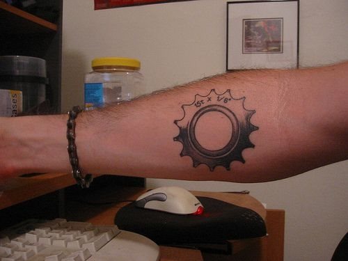 Rueda de engranaje que ha sido tatuada en el antebrazo junto con los números que determinan sus dimensiones y el tipo de engranaje es.