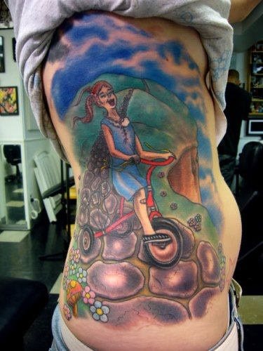 Colorido tatuaje de una nia en tirciclo sobre un camino de piedras Colorido tatuaje de una nia en tirciclo sobre un camino de piedras