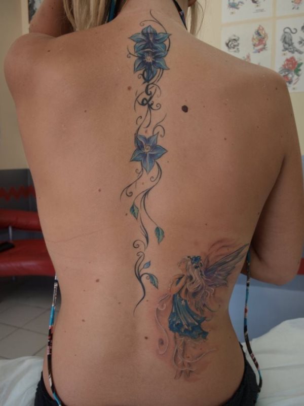 Diseo de grandes dimensiones que encaja varias flores que recorren la columna vertebral de esta chica con un hada en la parte inferior derecha de la espalda Diseo de grandes dimensiones que encaja varias flores que recorren la columna vertebral de esta chica con un hada en la parte inferior derecha de la espalda