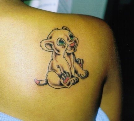 Tatuaje de un cachorro de león sonriente sobre la espalda de esta chica, al tattoo se le han añadido unos ojos de color verde y las palmas de las patas, cola y nariz en color rosa, un diseño muy sencillo que hacen de él un tattoo muy simpático Tatuaje de un cachorro de león sonriente sobre la espalda de esta chica, al tattoo se le han añadido unos ojos de color verde y las palmas de las patas, cola y nariz en color rosa, un diseño muy sencillo que hacen de él un tattoo muy simpático