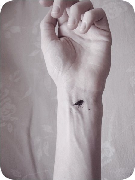 Tatuaje de la silueta de un pequeo pjaro que parece estar comiendo Tatuaje de la silueta de un pequeo pjaro que parece estar comiendo